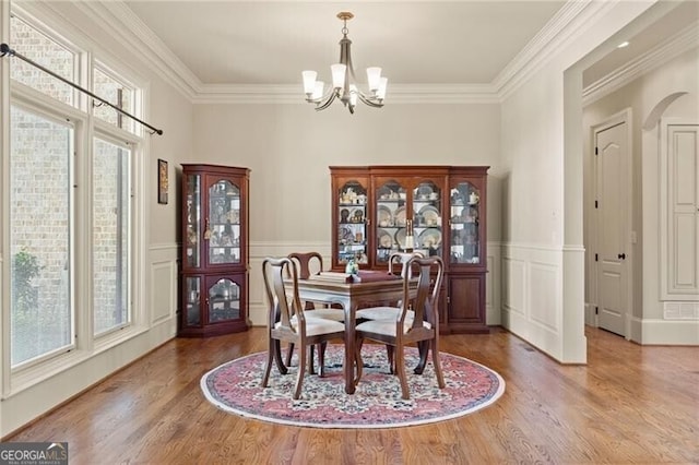 dining area with a chandelier, hardwood / wood-style floors, and crown molding