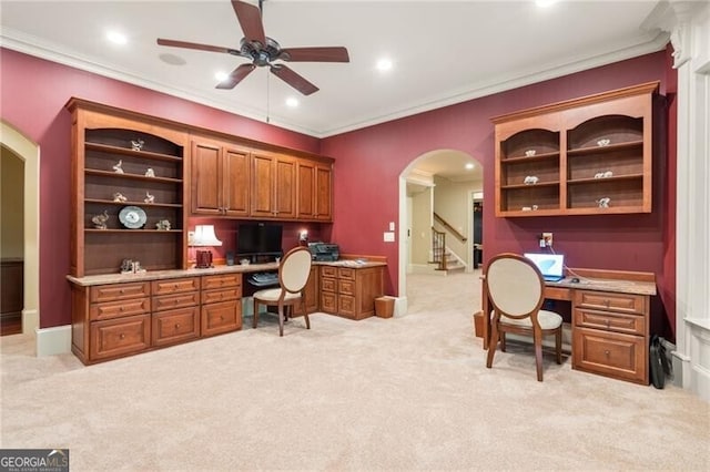 office area featuring built in desk, ornamental molding, light carpet, and ceiling fan