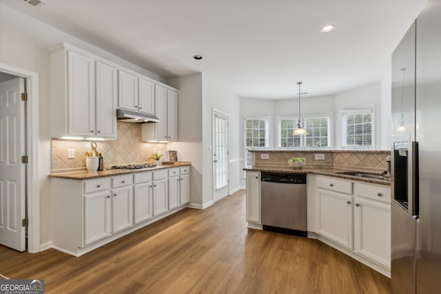 kitchen with dark stone countertops, white cabinetry, light hardwood / wood-style floors, and appliances with stainless steel finishes