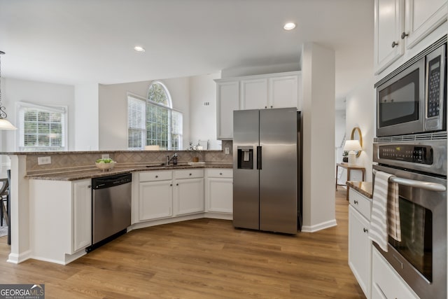 kitchen with stainless steel appliances, white cabinetry, and a healthy amount of sunlight