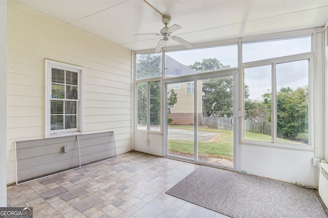 unfurnished sunroom featuring a healthy amount of sunlight and ceiling fan