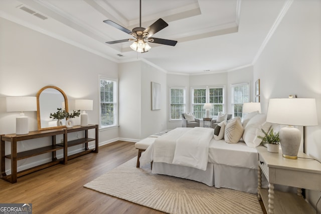 bedroom with wood-type flooring, crown molding, ceiling fan, and a raised ceiling