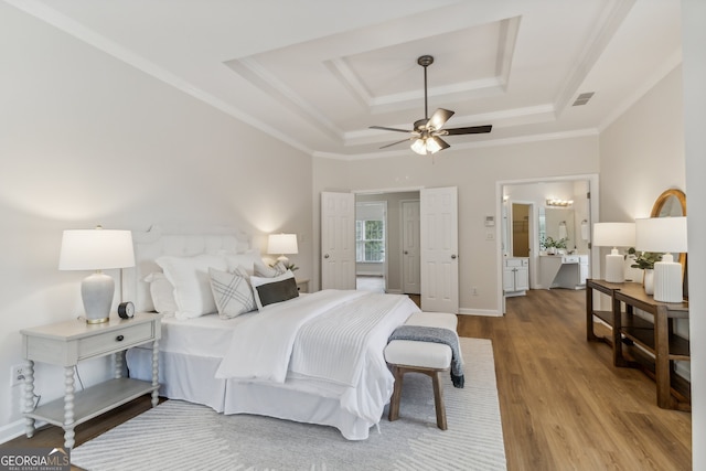 bedroom featuring ceiling fan, a tray ceiling, connected bathroom, and hardwood / wood-style floors