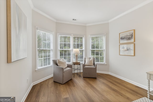 sitting room with light wood-type flooring and crown molding