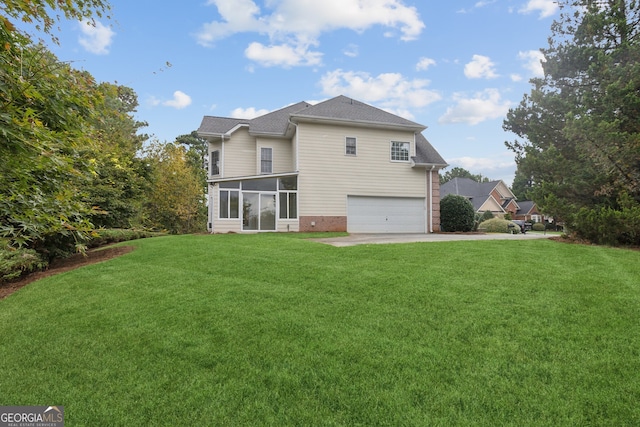 rear view of property with a sunroom, a yard, and a garage