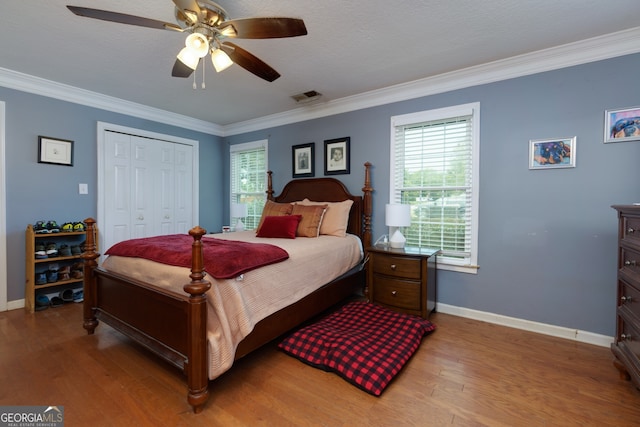 bedroom with a closet, a textured ceiling, hardwood / wood-style flooring, crown molding, and ceiling fan