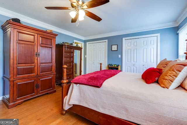 bedroom featuring ornamental molding, multiple closets, light hardwood / wood-style floors, and ceiling fan