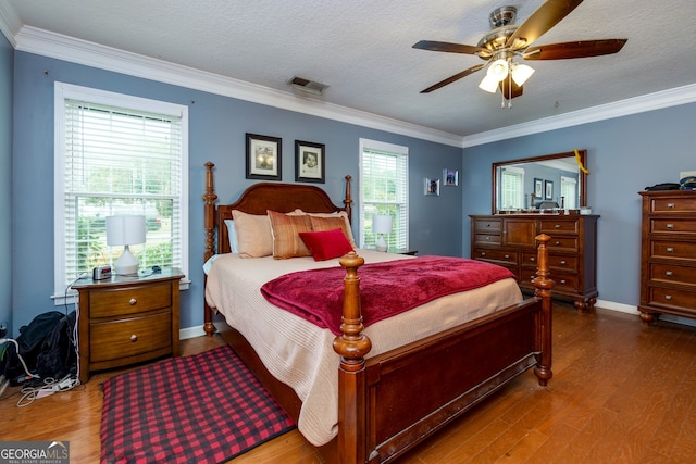 bedroom featuring ceiling fan, hardwood / wood-style flooring, ornamental molding, and a textured ceiling