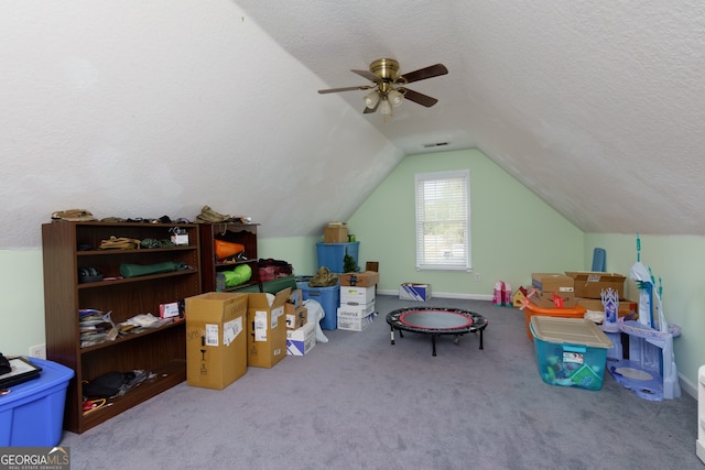 game room with a textured ceiling, vaulted ceiling, ceiling fan, and light colored carpet