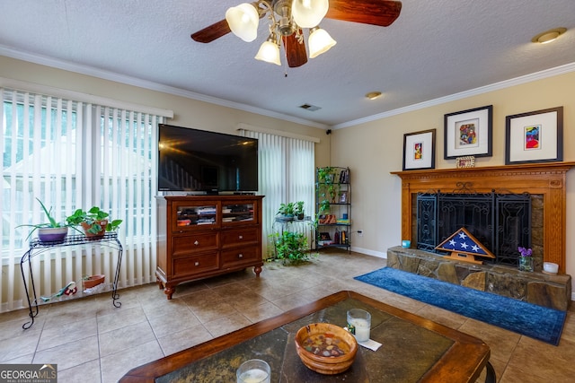 living room featuring light tile patterned flooring, a fireplace, a textured ceiling, ceiling fan, and ornamental molding