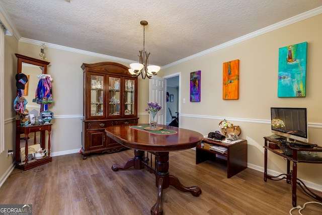 dining space with ornamental molding, an inviting chandelier, a textured ceiling, and hardwood / wood-style floors