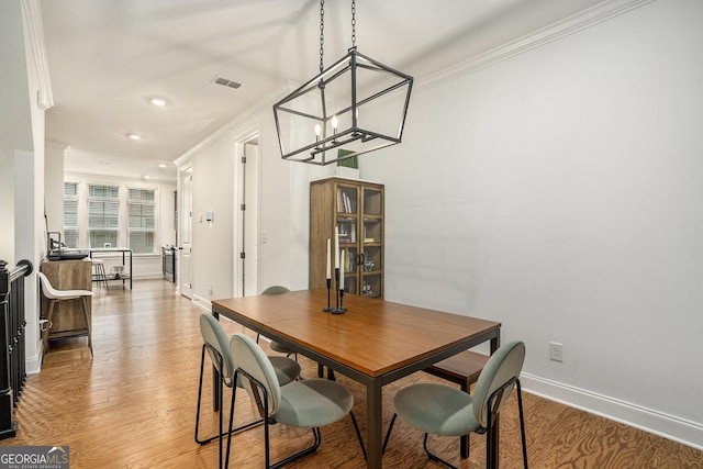 dining space with crown molding and light hardwood / wood-style flooring