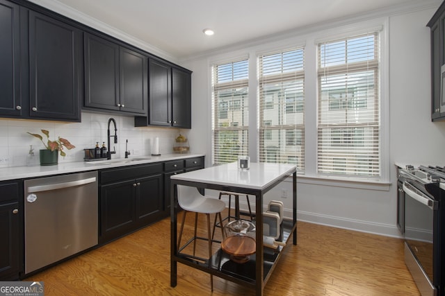 kitchen featuring decorative backsplash, appliances with stainless steel finishes, light wood-type flooring, ornamental molding, and sink