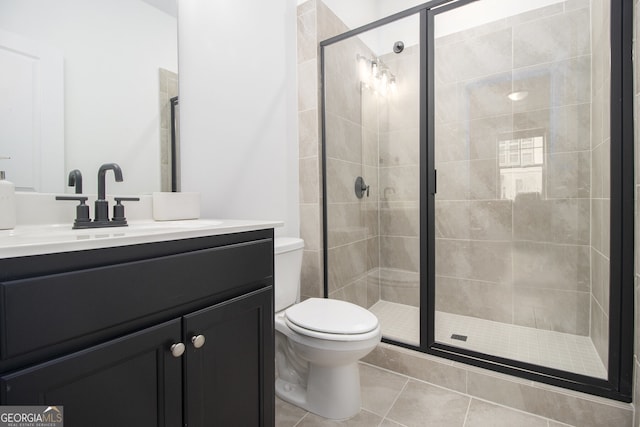 bathroom with tile patterned floors, vanity, a shower with shower door, and toilet