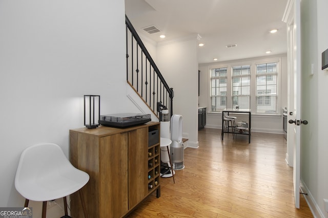 entrance foyer with light hardwood / wood-style floors and crown molding