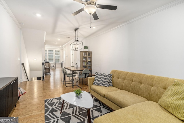 living room featuring ceiling fan with notable chandelier, light hardwood / wood-style flooring, and crown molding