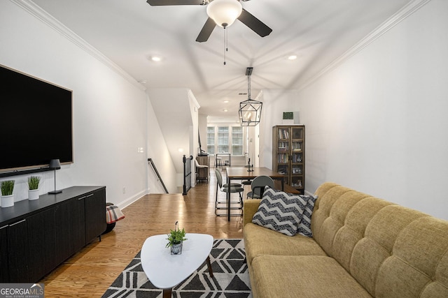 living room featuring ceiling fan with notable chandelier, light hardwood / wood-style floors, and crown molding