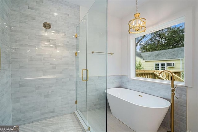 bathroom featuring plus walk in shower, tile patterned floors, a notable chandelier, and tile walls