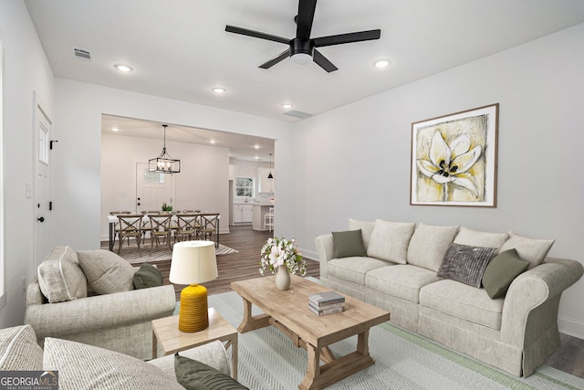 living room featuring hardwood / wood-style flooring and ceiling fan with notable chandelier