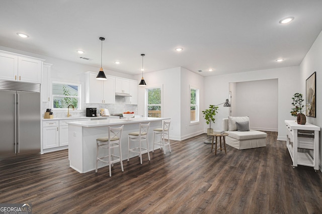 kitchen with built in fridge, a kitchen island, dark wood-type flooring, white cabinetry, and hanging light fixtures