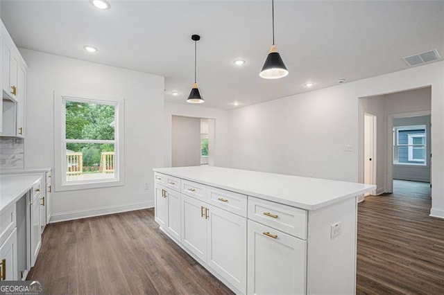 kitchen with decorative light fixtures, backsplash, dark wood-type flooring, white cabinetry, and a center island