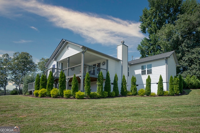 rear view of property with a balcony, a garage, and a lawn