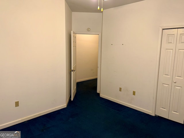 unfurnished bedroom with dark colored carpet and a closet