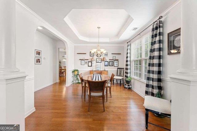 dining area featuring a chandelier, hardwood / wood-style floors, a raised ceiling, and crown molding