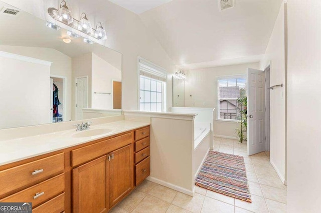 bathroom featuring tile patterned flooring, vanity, vaulted ceiling, and a bathing tub