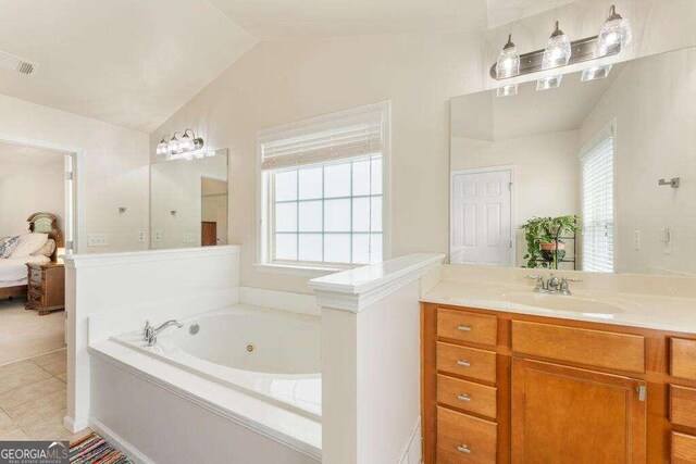 bathroom featuring tile patterned flooring, vanity, a tub to relax in, and vaulted ceiling