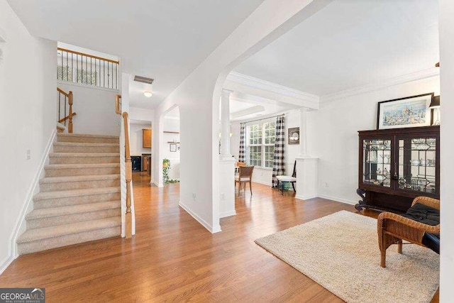 foyer entrance with crown molding and wood-type flooring