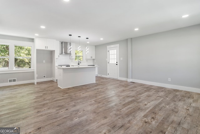 kitchen with wall chimney range hood, dark wood-type flooring, stainless steel appliances, sink, and white cabinets