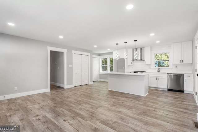 kitchen with appliances with stainless steel finishes, white cabinetry, light hardwood / wood-style floors, wall chimney exhaust hood, and sink