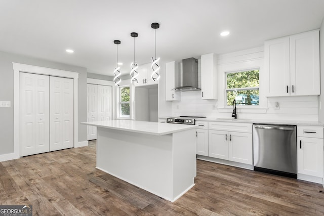 kitchen featuring wall chimney range hood, white cabinets, stainless steel appliances, and sink