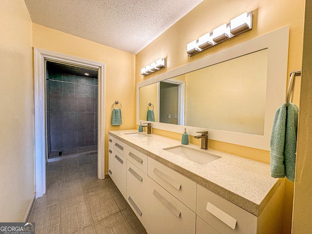 bathroom with vanity, a tile shower, a textured ceiling, and tile patterned floors