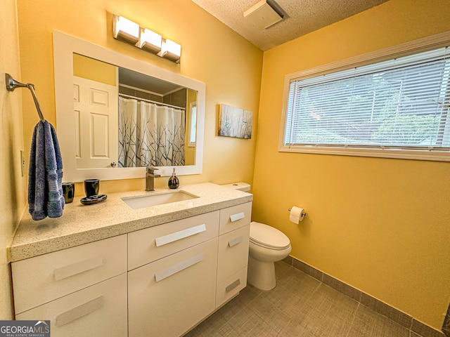 bathroom featuring a textured ceiling, vanity, and toilet