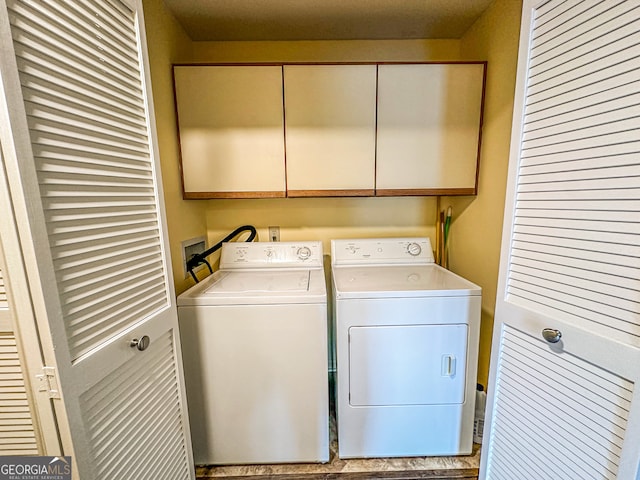 clothes washing area featuring cabinets and washer and dryer