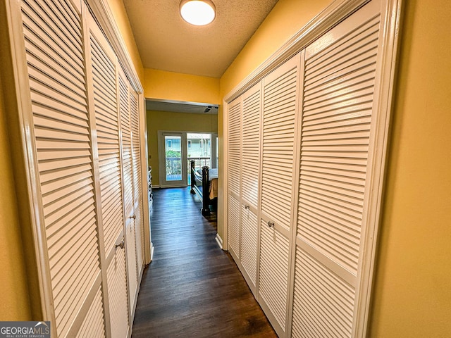 hallway featuring a textured ceiling and dark hardwood / wood-style floors