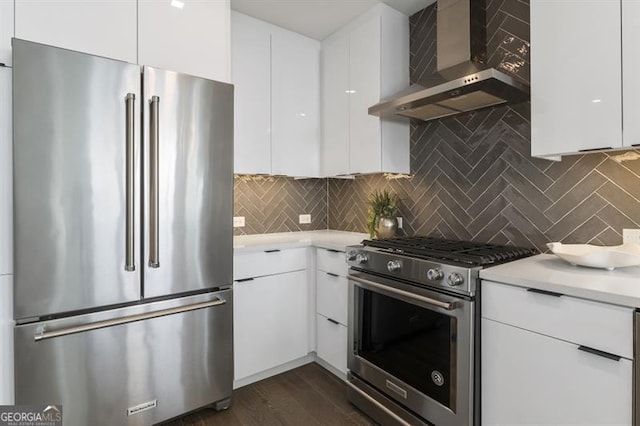 kitchen featuring white cabinets, wall chimney range hood, tasteful backsplash, and premium appliances