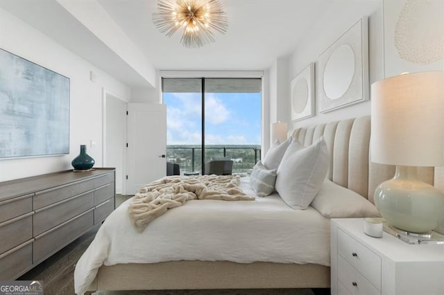 bedroom with a wall of windows, a chandelier, dark hardwood / wood-style floors, and access to exterior