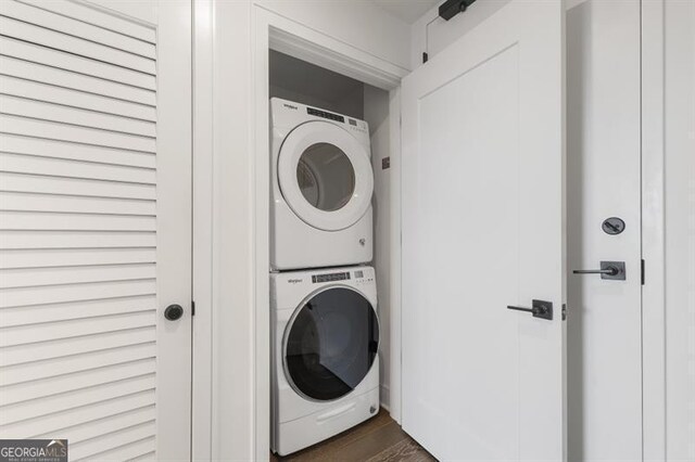 clothes washing area with dark hardwood / wood-style floors and stacked washer / dryer