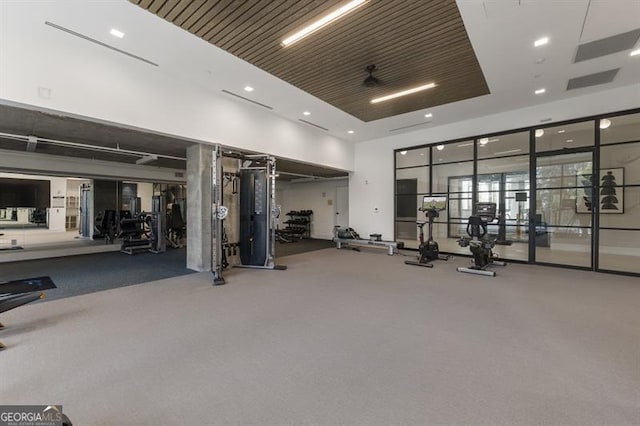 exercise room with ceiling fan and a towering ceiling