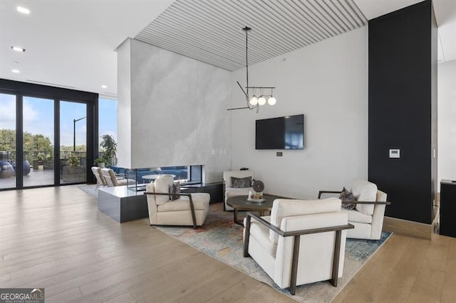 living room featuring light hardwood / wood-style flooring, a wall of windows, and a notable chandelier