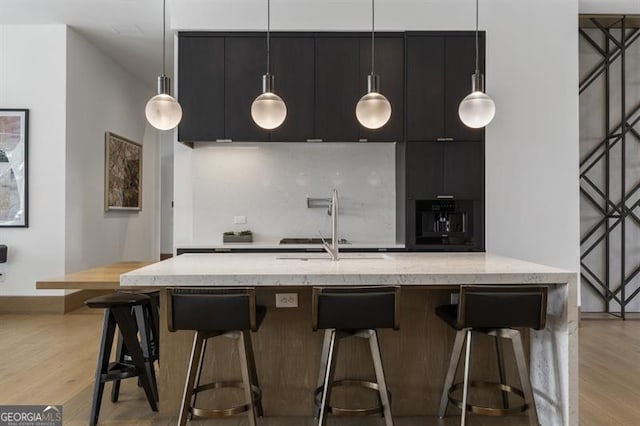 kitchen featuring a kitchen breakfast bar, light hardwood / wood-style flooring, sink, and hanging light fixtures