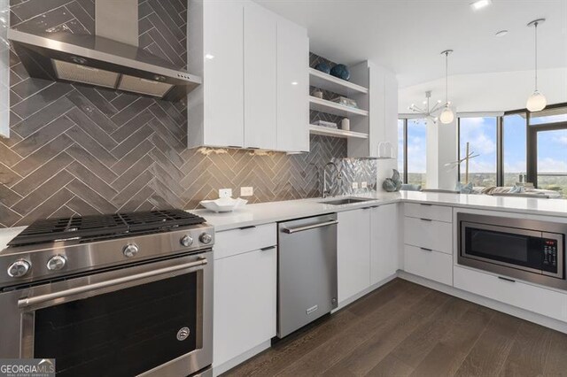 kitchen with backsplash, appliances with stainless steel finishes, decorative light fixtures, and white cabinets