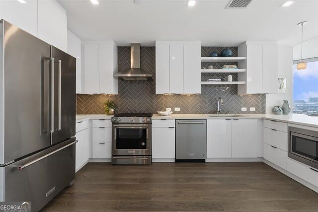 kitchen with wall chimney exhaust hood, appliances with stainless steel finishes, sink, and white cabinets