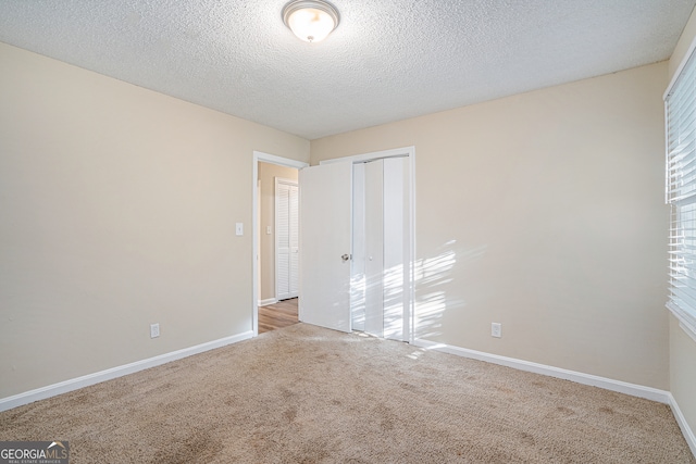 spare room with a textured ceiling and light colored carpet