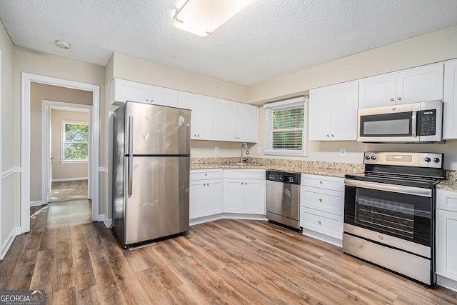 kitchen with stainless steel appliances, white cabinets, hardwood / wood-style flooring, and sink