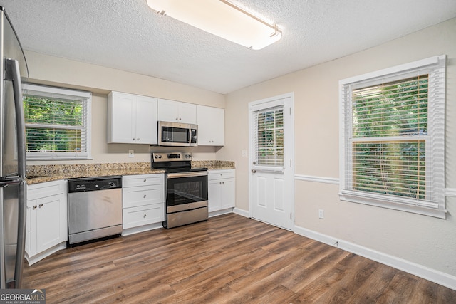 kitchen with stainless steel appliances, plenty of natural light, and white cabinetry