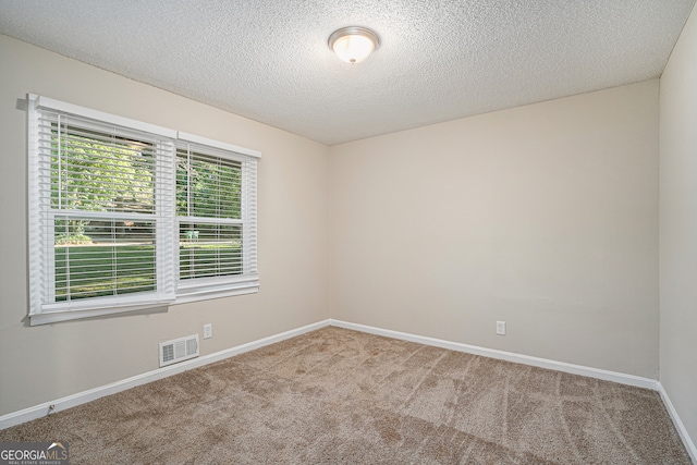 carpeted empty room with a textured ceiling